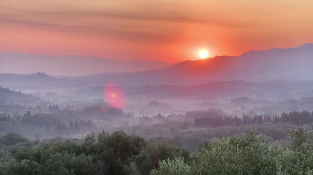 Golden morning sunrise over misty mountain valley and olive groves in Corfu, Greece