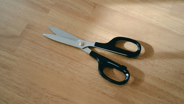 Black handled scissors on a wooden table