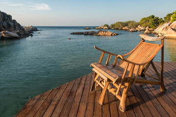 Fototapeta premium Wooden armchair at resort patio by sea at sunrise, Ko Man Klang, Rayong