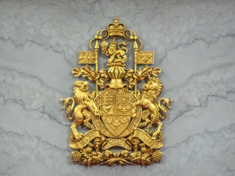 Ottawa, Ontario, Canada. Sep 10, 2026. Golden Royal Coat of Arms of Canada relief mounted on marble wall inside government building.