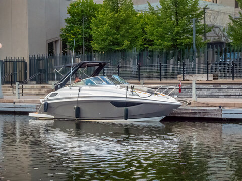 OTTAWA, ONTARIO, CANADA. SEPTEMBER 10, 2026. White motorboat docked at a canal boardwalk with green trees in background.