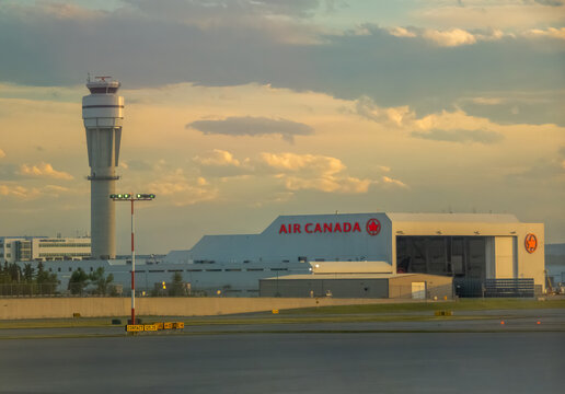 CALGARY, ALBERTA, CANADA. SEPTEMBER 10, 2026. Air Canada maintenance hangar and control tower at airport during golden hour sunset.