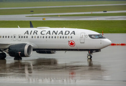OTTAWA, ONTARIO, CANADA. SEPTEMBER 10, 2026. Side view of Air Canada airplane nose on wet airport tarmac with reflections.