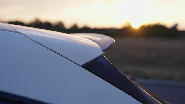 White car spoiler with sunset in background