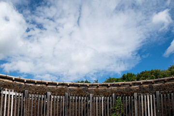 Fototapeta premium Curved wooden graduation tower structure against a bright blue cloudy sky