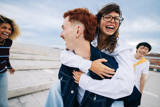 Friends laughing during piggyback ride on rooftop