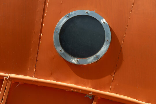 Circular window on a bright orange metal wall
