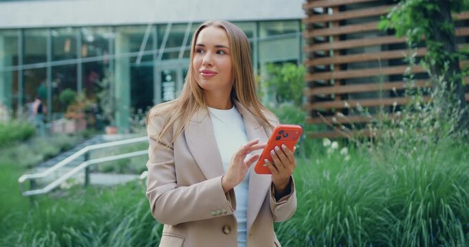 Close up of attractive young with blond hair woman standing and using phone. Outdoors