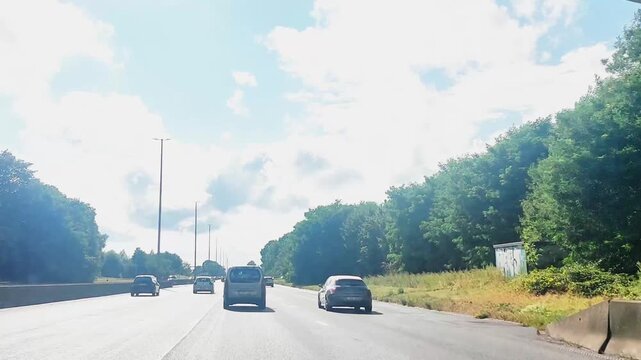Driving under a bridge on the motorway surrounded by trees and blue skies