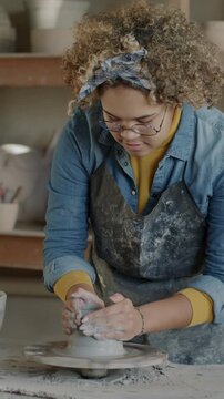 Slow motion of African American potter working with clay on throwing wheel enjoying hobby in workshop. Creative people and small business concept.