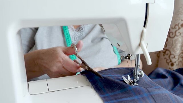 Senior Woman Cutting Fabric with Scissors During Home Sewing Project