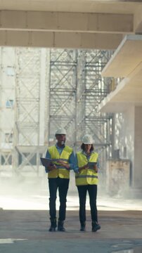 Vertical Screen. Building Construction Site with Workers. Real Estate Building Construction Site: Architect and Contractor Walk Toward Floor Edge, Talking About Project. Rear View Slow Motion Tracking