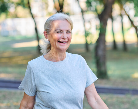 Smiling active mature elderly woman jogging running or speed walking  in the park