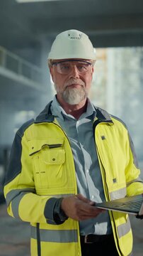 Vertical Screen. Building Construction Site with Workers. Portrait of Structural Engineer Using Laptop Computer for Blueprint Specifications. Data Center Facility Hyperscale Building