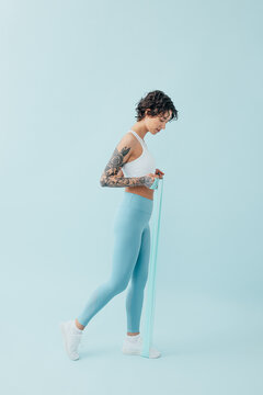 Full length of a young, slim woman practicing with a resistance band