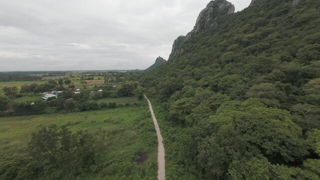 Aerial descends to narrow road below rugged limestone peaks, Khao No