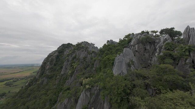 Proximity flight past jagged, shattered limestone spires by farmland