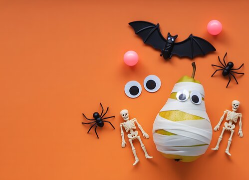 Festive halloween decorations including mummy bats spiders and googly eyes on orange background