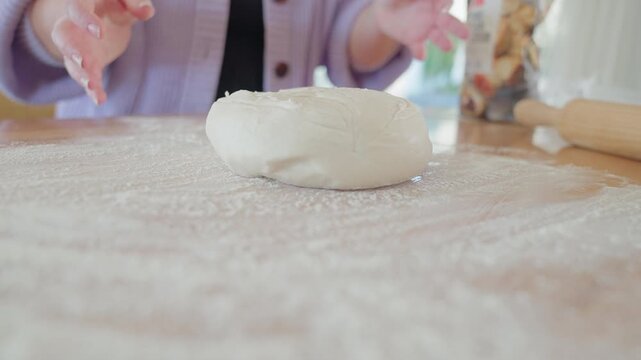 Dough ball being dropped onto kitchen counter in a bright and open kitchen. Pizza and bread on top of counter top and flour