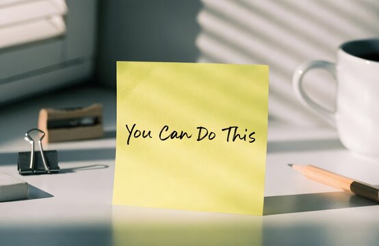 Yellow sticky note with motivational message on desk workspace
