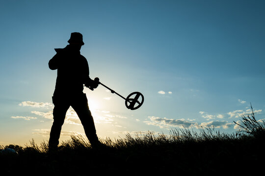 Step by Step, A Treasure Hunter Moves Across the Field at Dusk