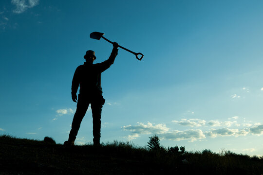 Victory Pose, Man Raising Shovel Skyward in Celebration
