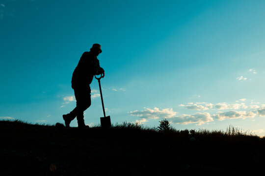Man in a Hat Resting on His Shovel in Quiet Contemplation