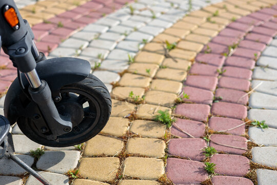 Front wheel of an electric scooter on a colorful paved path