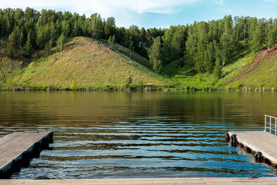 Wooden piers on a calm lake with green forested hills in summer