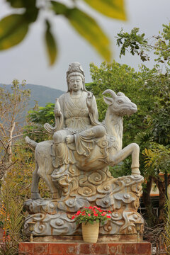 Stone Guanyin statue sitting on lunar zodiac goat mount, traditional Asian astrology horned ram sheep sculpture for peace and harmony