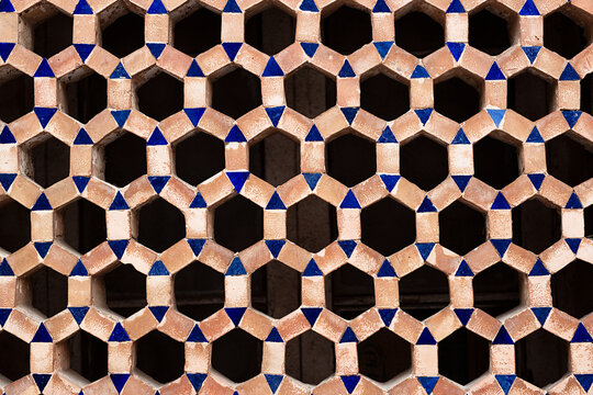 Geometric terracotta lattice screen with blue tile accents on Bibi Khanym Mosque in Samarkand. Hexagonal openwork pattern ideal for architecture, heritage, and design projects.