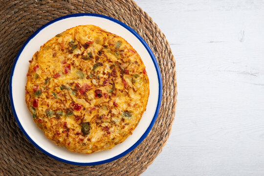 Top view of a Spanish potato omelet with green and red peppers. Traditional recipe. 