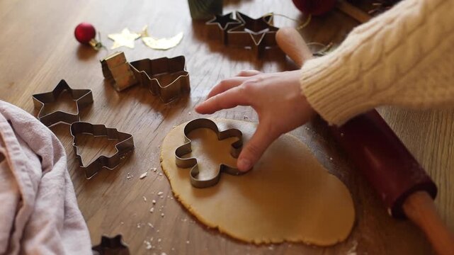 Gingerbread  baking video. Person Cutting Out Gingerbread Cookie Shapes from Rolled Dough on Wooden Table with Holiday Decor. Christmas Cooking, Festive Food