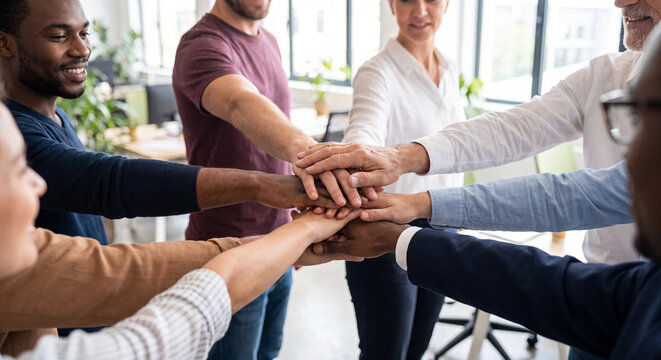 Diverse team stacking hands together in office unity teamwork business concept photo