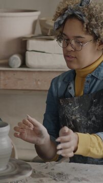 Caucasian man and African American woman making pot together working with clay in workshop. Interesting hobby and creative people concept.