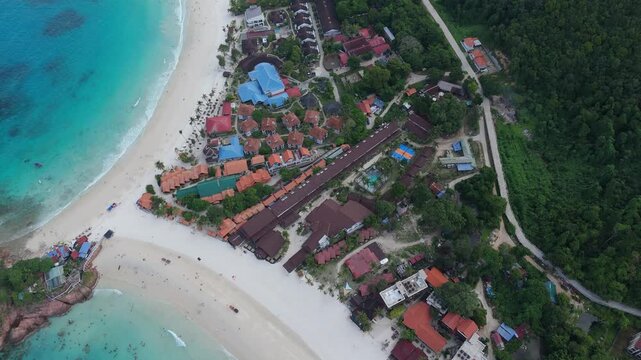 Aerial top down view of beachfront resort villas nestled among palm trees along white sand beach, Redang Island, Malaysia