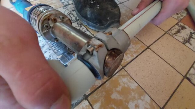 Plumber welding plastic PPR pipes with a socket fusion heating machine close-up