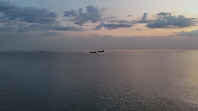 Wide aerial view of cargo and commercial vessels navigating the R&iacute;o de la Plata near Montevideo at sunset, under a calm sky with soft evening light.