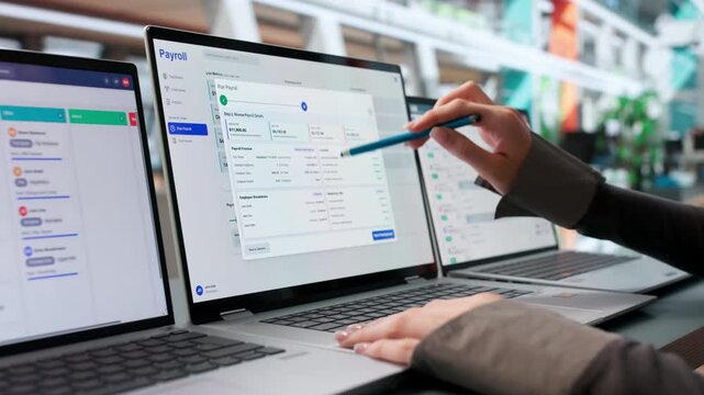 HR Manager Carefully Reviews Payroll Software Data On Laptop