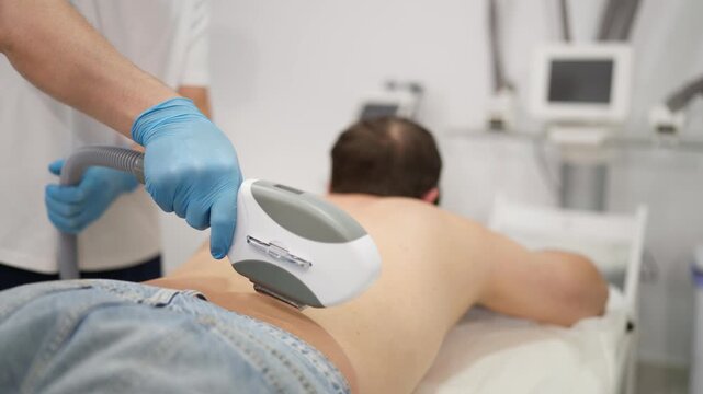 Male client receiving professional laser treatment on his back, representing men's grooming, body hair removal, smooth skin, personal hygiene and modern aesthetic care