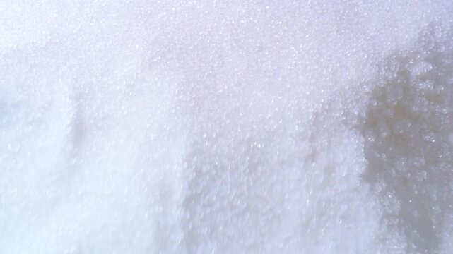 White snow crystals cover a textured icy surface in closeup winter setting