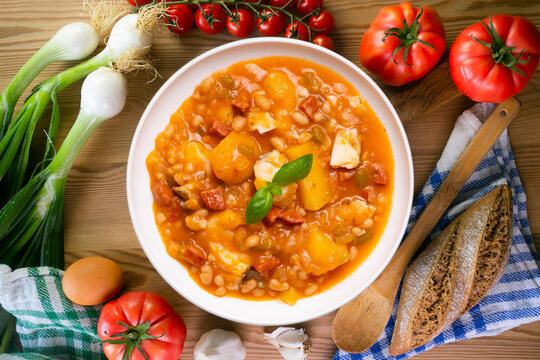 A close-up overhead view of a delicious cod and chorizo stew, garnished with basil