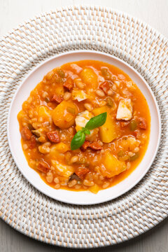 A close-up overhead view of a delicious cod and chorizo stew, garnished with basil