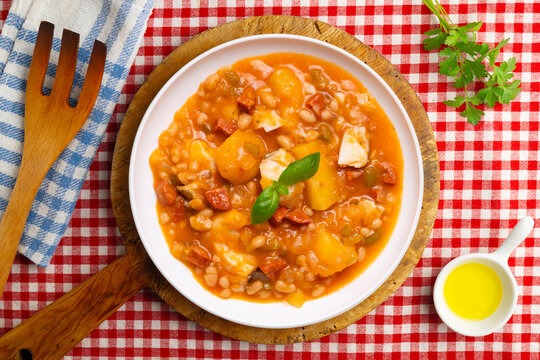 A close-up overhead view of a delicious cod and chorizo stew, garnished with basil