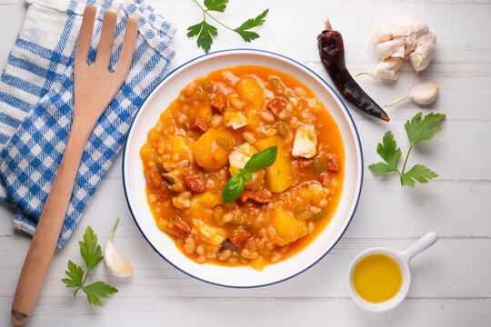 A close-up overhead view of a delicious cod and chorizo stew, garnished with basil