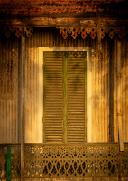 Weathered corrugated metal house facade with green shutters and ornate wooden fretwork, Benguela Province, Benguela, Angola