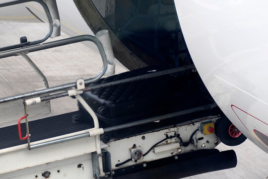 Luggage being loaded into an aircraft cargo hold via a conveyor belt on the airport tarmac