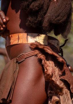 Close-up of a woman's waist wearing a carved patterned belt over a beaded band and goat fur skirt, Cunene Province, Oncocua, Angola