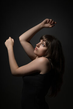 Young woman posing in dramatic lighting with expressive movement