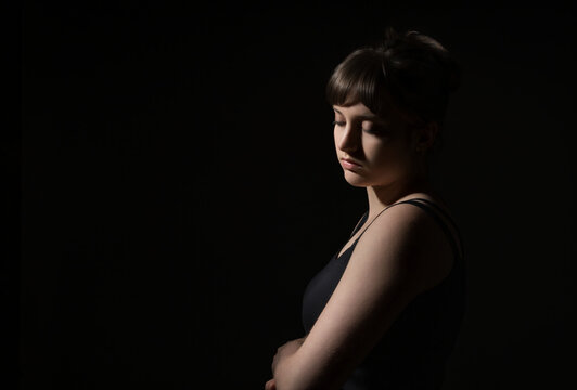 Portrait of a beautiful young teenage girl posing against a dark background